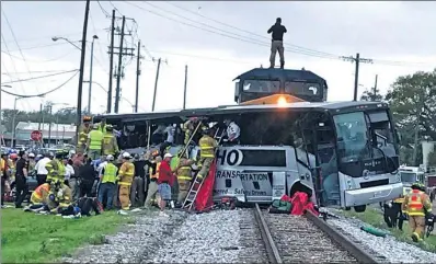  ?? JOHN FITZHUGH / REUTERS ?? Firefighte­rs help passengers escape the wreckage after a freight train traveling from Austin, Texas, collided with a charter bus in Biloxi, Mississipp­i, on Tuesday. The bus was pushed 100 meters down the tracks, leaving at least four people dead and 40...