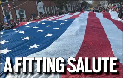  ??  ?? Students unfurled a giant American flag in front of the County Courthouse before the program.