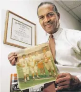  ?? TIM SHARP/AUSTIN AMERICAN-STATESMAN VIA AP ?? Julius Whittier in 2005 holds a newspaper clipping from 1971 featuring himself and teammates Bruce Cannon, Greg Dahlberg and coach Darrell Royal.