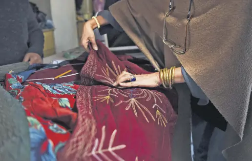  ??  ?? An Afghan tailor works on a cotton fabric piece at Zarif Design House in Kabul.