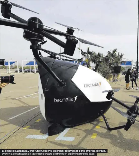  ??  ?? El alcalde de Zaragoza, Jorge Azcón, observa el aerotaxi desarrolla­do por la empresa Tecnalia, ayer en la presentaci­ón del laboratori­o urbano de drones en el párking sur de la Expo.