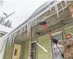  ??  ?? Ha Thao of Wausau, Wis., chips icicles off his porch Tuesday. Several inches of snow fell overnight.