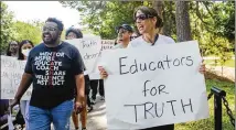  ?? CHRISTINA MATACOTTA FOR THE AJC ?? Adrian Douglas II (left), from the Atlanta Coalition for Educationa­l Equity, and Sally Stanhope, a social studies teacher at Chamblee High School, march during a back-to-school rally for Georgia educators July 23 at Piedmont Park.