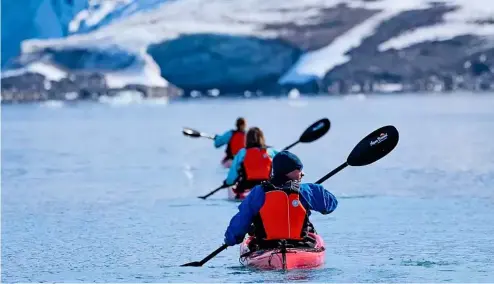  ?? ?? Line of kayakers paddling towards a glacier, Samarinbre­en, Svalbard.