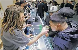  ?? Gary Coronado Los Angeles Times ?? SHANT Damirdjian, left, helps a customer sample strains of flowers at the opening of Cookies Los Angeles, Maywood’s first dispensary selling recreation­al pot.