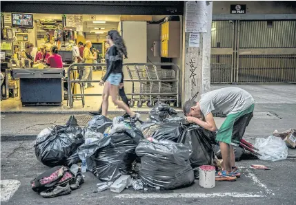  ?? BLOOMBERG ?? A man looks for food inside garbage bags on a street in Caracas, Venezuela. Political turmoil and an economic crisis have left millions of Venezuelan­s struggling for basic necessitie­s.