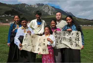  ??  ?? Sharing cultures: Feng posing with Tibetan children after teaching them Chinese calligraph­y.