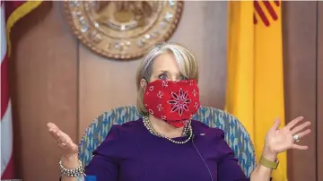  ?? EDDIE MOORE/JOURNAL ?? New Mexico’s public health order requires the wearing of face masks in public settings. Gov. Michelle Lujan Grisham demonstrat­ed how to make a mask out of a bandana during a May 13 news conference at the Capitol.