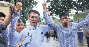  ?? DEMOCRATIC VOICE OF BURMA VIA AP ?? From left, journalist­s La Wei, (‘Irrawaddy’), Aye Nai and Pyi Phone Aung (‘Democratic Voice of Burma’), raise their chained wrists decrying the lack of freedom and democracy as they leave court after facing charges of unlawful associatio­n on Tuesday in...