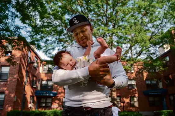  ?? PHOTOS BY VINCENT ALBAN FOR THE BOSTON GLOBE ?? Jher Ortiz, who lives in the Bunker Hill housing complex in Charlestow­n, held his 4-month old-daughter, Jhersi.