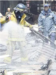  ??  ?? Firefighte­rs continue the cooling-down process after a fire destroyed the Ray Ray Ground market in downtown Kingston yesterday.