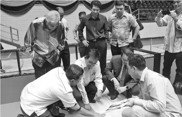  ??  ?? Karim (squatting at second left) with Aziz (second right) checking out the floor while (from left, standing) Wahap and Kameri and others look on at Sarawak Indoor Stadium in Petra Jaya yesterday. — Photo by Harry Ilias