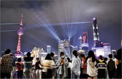  ?? ZHOU DONGCHAO / FOR CHINA DAILY ?? People watch a light show at the Bund in Shanghai in September.