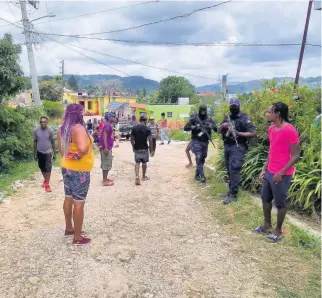  ?? HOPETON BUCKNOR ?? Police personnel stand guard outside Spicy Hill Farm in Trelawny, after the manager reportedly shot Kimorlay Forbes to death.