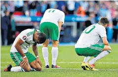  ??  ?? Down and out: Northern Ireland’s players sink to the turf after their defeat to Wales