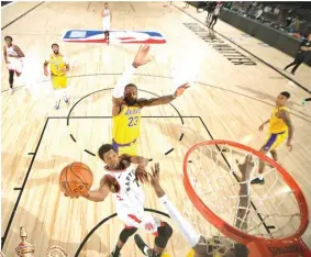  ?? BILL BAPTIST/NBAE/GETTY IMAGES VIA AFP ?? DOMINASI: Point guard Toronto Raptors Kyle Lowry menembakka­n bola ke ring saat melawan LA Lakers di The Arena, ESPN WWoSC, Orlando, Florida, kemarin WIB.