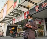  ??  ?? BEIJING: A woman wearing a face mask uses her mobile phone at the entrance of Auchan supermarke­t in Beijing.—