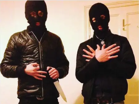  ??  ?? A SINISTER masked man brandishes a knife as his companion makes the crossed-hands gesture in a photo, captioned ‘Burglars in Croydon’, posted on a Facebook page set up to help Albanians get to London