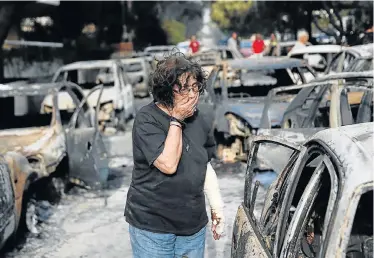  ?? Picture: COSTAS BALTAS/REUTERS ?? IN SHOCK: A woman searches for her dog following a wildfire at the village of Mati in Greece