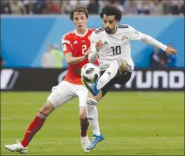  ?? The Associated Press ?? Egypt’s Mohamed Salah, right, controls the ball while being challenged by Russia’s Mario Fernandes during Tuesday’s game, which Russia won 3-1.