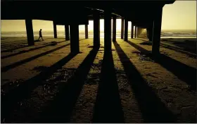  ?? ERIC GAY, FILE - THE ASSOCIATED PRESS ?? In this Nov. 21 photo, a man walks along the beach under the Horace Caldwell Pier at sunrise in Port Aransas, Texas.