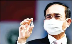  ?? AFP ?? Thai Prime Minister Prayut Chan-o-cha holds a vial of the Coronavac Covid-19 vaccine, developed by China’s Sinovac firm, as its shipment arrived in Bangkok on Wednesday.