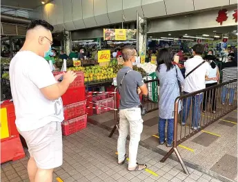  ??  ?? Shoppers observe the one-metre social distancing as they queue outside Farley Supermarke­t at Salim Road.