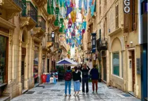  ?? ?? Visitors in the city of Valletta stop to photograph flags suspended over the ancient streets.