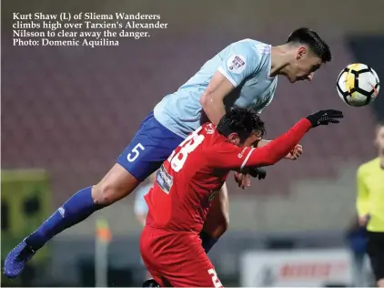  ??  ?? Kurt Shaw (L) of Sliema Wanderers climbs high over Tarxien's Alexander Nilsson to clear away the danger. Photo: Domenic Aquilina