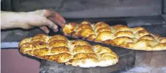  ??  ?? A bread baker takes two special round baked flatbreads referred to as the Ramazan pide, made from an oven-baked enriched dough and sprinkled with nigella and sesame seeds on top, out of the oven, Tokat, Turkey, April 13, 2021.