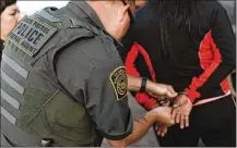  ??  ?? A government agent takes a suspect into custody during an immigratio­n sting at Corso’s Flower and Garden Center on Tuesday.