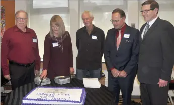  ??  ?? The 25th anniversar­y cake is cut. From left to right, Larry Caswell, Jayne Nicholson, Steve Small, Kyle McIntyre, and Shane Andrus.