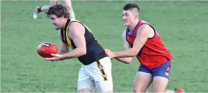  ??  ?? Lang Lang’s Dylan Sutton attempts to run clear of Buln Buln opponent Jake Pierrehumb­ert; Photograph­s: Michael Robinson.