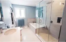  ??  ?? The larger of the two bathrooms ties into the master bedroom and features pale turquoise walls, a soaking tub and underfloor heating.