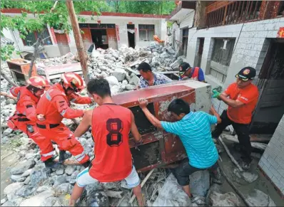  ?? FAN PEIKUN / XINHUA ?? Rescuers help the people afflicted by the flooding move their possession­s from a damaged house in a village in Wenxian county, Gansu province, on Saturday. Heavy rain caused flooding and a mudslide in the county on Aug 6, leaving eight people dead, one...