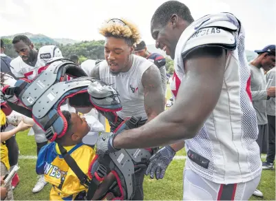  ?? Brett Coomer photos / Houston Chronicle ?? Texans linebacker­s Whitney Mercilus, left, Benardrick McKinney, center, and Shakeel Rashad help hand out shoulder pads to kids from West Virginia Youth Football after Friday’s practice.