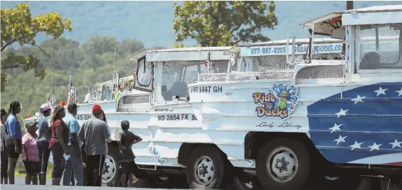  ?? AP PHOTO ?? TRAGEDY IN MISSOURI: People in Branson, Mo., look at idled duck boats yesterday, two days after 17 people were killed on a tour. Laws regulating the tourist vehicles in Massachuse­tts were updated two years ago, improving safety, but could be changed...