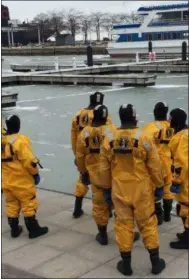  ?? ADAM DODD — THE NEWS HERALD ?? Members of the Cleveland Fire Department look on as they prepare to venture out on to the icy surface of Lake Erie during cold water rescue training with the U. S. Coast Guard, Feb. 13th.