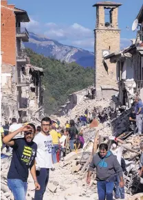  ?? MASSIMO PERCOSSI/ANSA VIA ASSOCIATED PRESS ?? Rescuers and residents of Amatrice, Italy, walk Wednesday amid the ruins left by a 6.1 magnitude earthquake that struck central Italy. The quake was felt as far away as Rome.