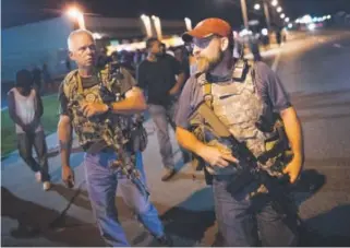  ??  ?? Oath Keepers with rifles walk along West Florissant Avenue as demonstrat­ors protested Monday in Ferguson, Mo., to mark one year since Michael Brown’s death. Scott Olson, Getty Images