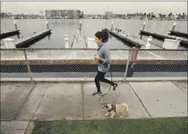  ?? Al Seib Los Angeles Times ?? POLLY AURITT AND CLEO take a run through Burton Chace Park in Marina del Rey Tuesday, as a weak storm sprinkled the Southland with precipitat­ion.