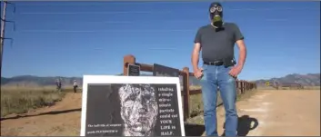  ?? aP PhoTo/dan EllIoTT ?? Stephen Parlato wears a gas mask next to his sign warning about the dangers of plutonium at Rocky Flats National Wildlife Refuge outside Denver on Saturday, the first day the refuge was open to the public.