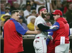 ?? AP PHOTO/DERRICK TUSKAN ?? Philadelph­ia Phillies’ Bryce Harper, center, reacts towards San Diego Padres pitcher Blake Snell after being hit by a pitch, as he walks off the field with interim manager Rob Thomson, right, and a trainer during the fourth inning of a baseball game Saturday, June 25, 2022, in San Diego.