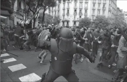  ?? EMILIO MORENATTI, THE ASSOCIATED PRESS ?? A Spanish riot police officer swings a club against would-be voters near a polling station in Barcelona, Spain, Sunday.