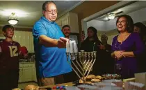  ?? Kevin D. Liles / Washington Post ?? Terence Arenson lights a menorah in his home in Dothan, Ala., with Lisa Priddle to his right.