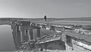  ?? SERGEY BOBOK/AFP VIA GETTY IMAGES ?? A resident crosses the Siverskyi Donets river on a temporary bridge Wednesday in a village east of Kharkiv, Ukraine, the same day Ukrainian President Volodymyr Zelenskyy visited the area.