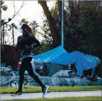  ?? RANDY VAZQUEZ — STAFF ARCHIVES ?? A tent can be seen in the distance as a person runs on the trail along Guadalupe River Park in San Jose on Feb. 2.