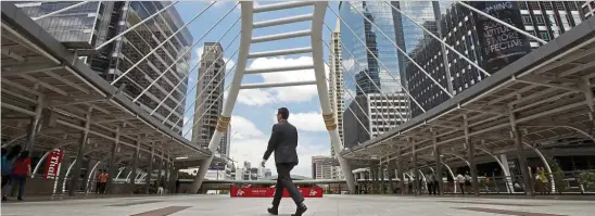  ??  ?? Slowest pace: A file picture showing a man walking in a business area in Bangkok. The central bank forecast economic growth at 2.8% for this year and 2.5% for 2019. — Reuters