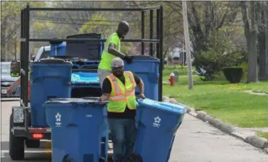  ?? MORNING JOURNAL FILE ?? Contractor­s from Texas-based WasteRec Waste Recycling Services Inc. deliver wheeled garbage cans to residentia­l properties in Lorain on April 17, 2017. Almost two years after Lorain began using the wheeled cans, or carts, for automated trash collection, some residents would like to have larger or more recycling containers.