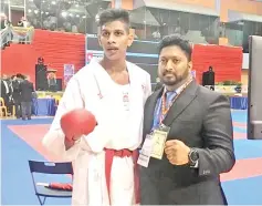  ??  ?? HARD-EARNED GOLD: Somanroy Arulveeran (left) celebrates with his coach Alexander Arulandu after a tough 2-1 win in the Male Kumite +84kg against Japan rival Ueyama Daina.